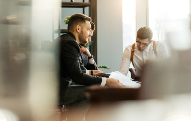 Three people surrounding a table going over paperwork
