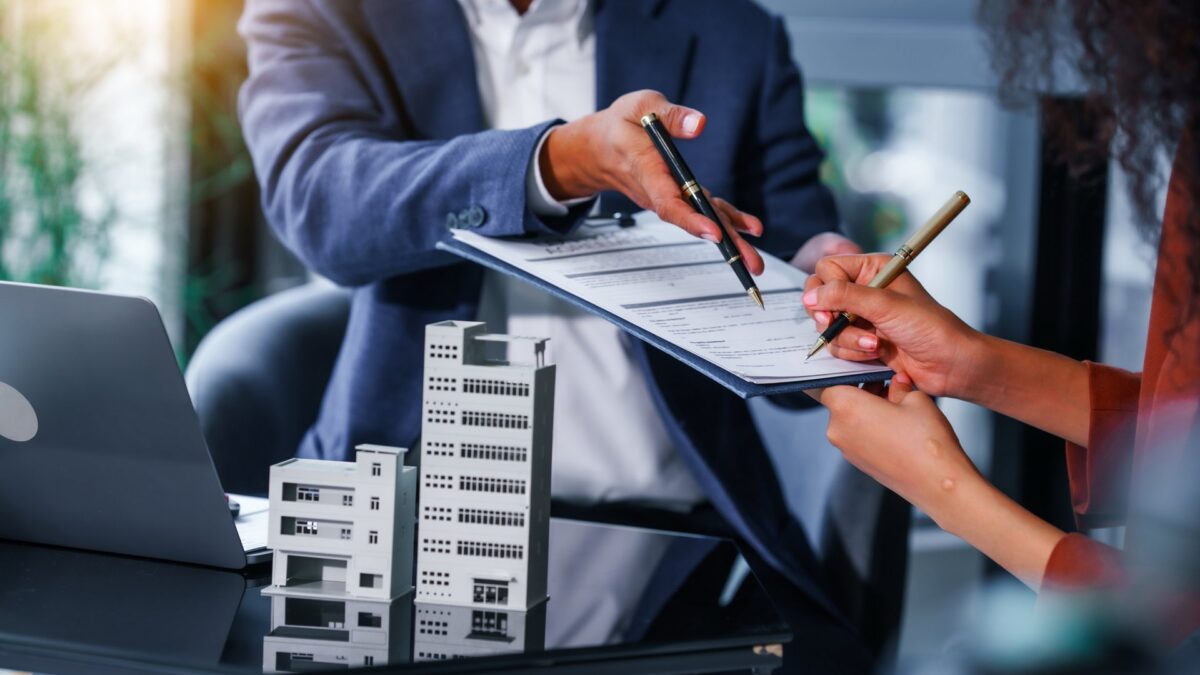 Two people sitting at a desk going over paperwork on a clipboard