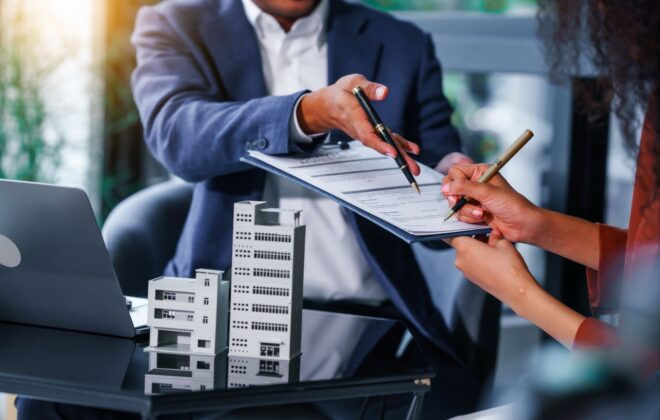 Two people sitting at a desk going over paperwork on a clipboard